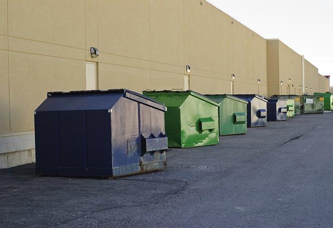 construction workers throw waste into a dumpster behind a building in Birchwood